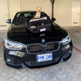Load image into Gallery viewer, BMW Bed plush pet bed designed like a black BMW sports car with side mirrors and headlights, shown with small dog inside on car hood
